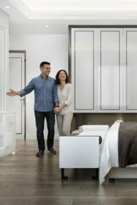 Matrimonio mostrándose felices por la nueva decoración y muebles de su dormitorio de matrimonio